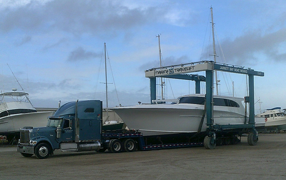 A semi truck preparing to haul a medium-sized boat.